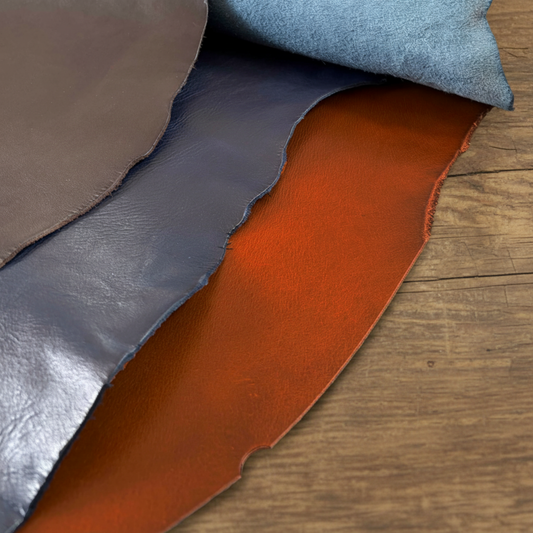 Close-up of leather samples in brown, blue, and tan on a wooden surface