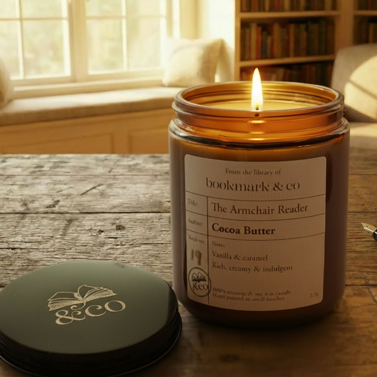 Candle in a jar labeled 'Dover & Co' on a wooden table with books and a pen in the background