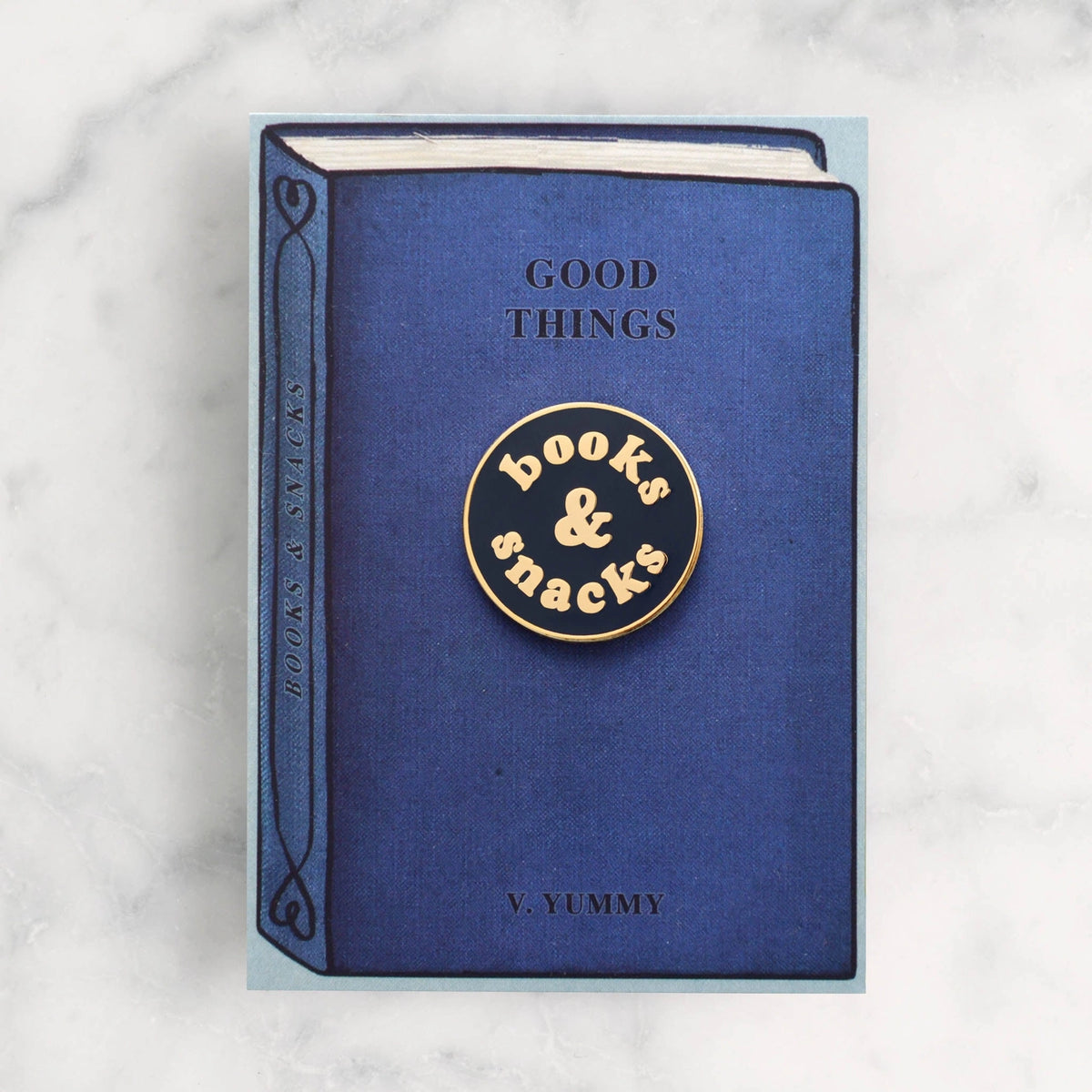 Blue book with 'books & snacks' emblem on a marble background