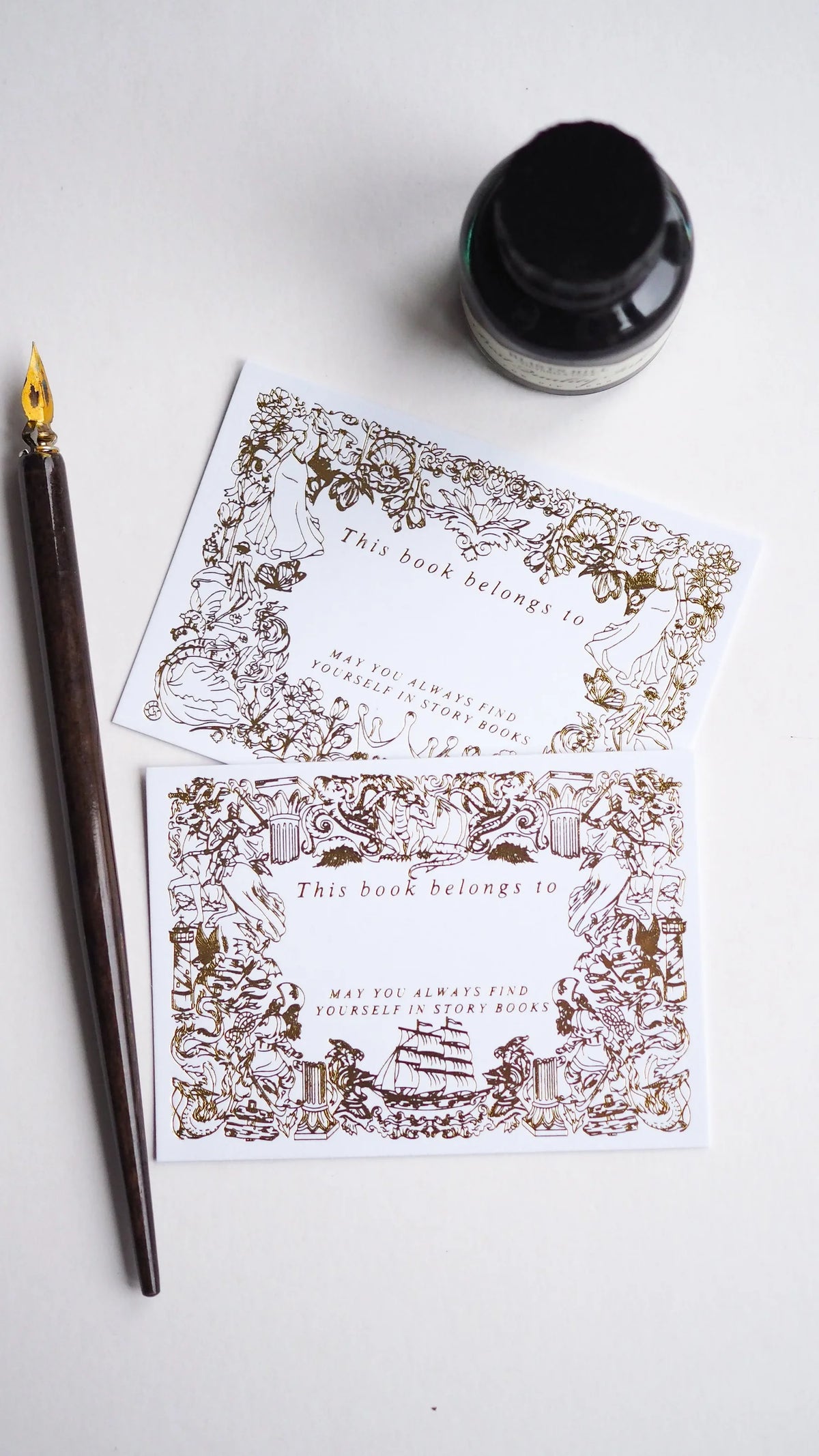 Decorative bookplates with intricate designs on a white surface with a fountain pen and ink bottle.
