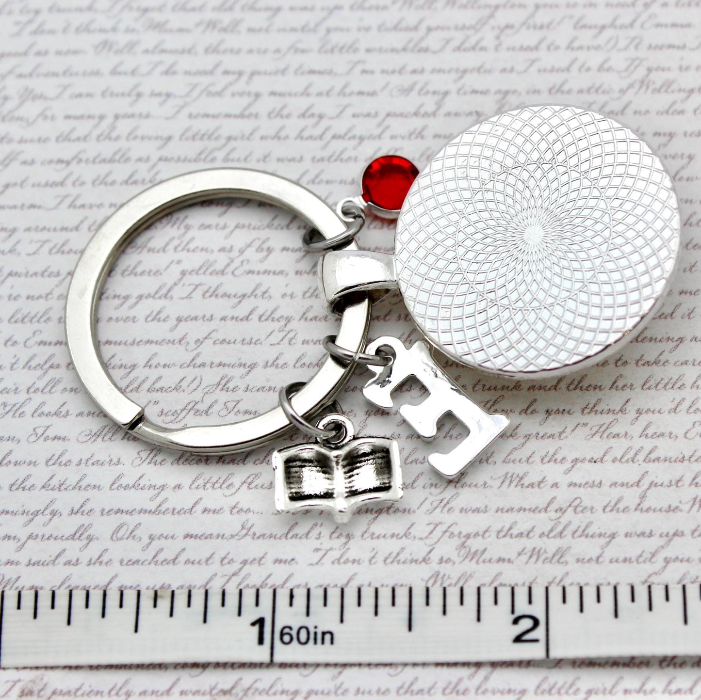 Keychain with round silver charm, red gem, and letter charms