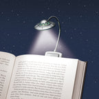 UFO-shaped reading lamp on an open book with a starry night background