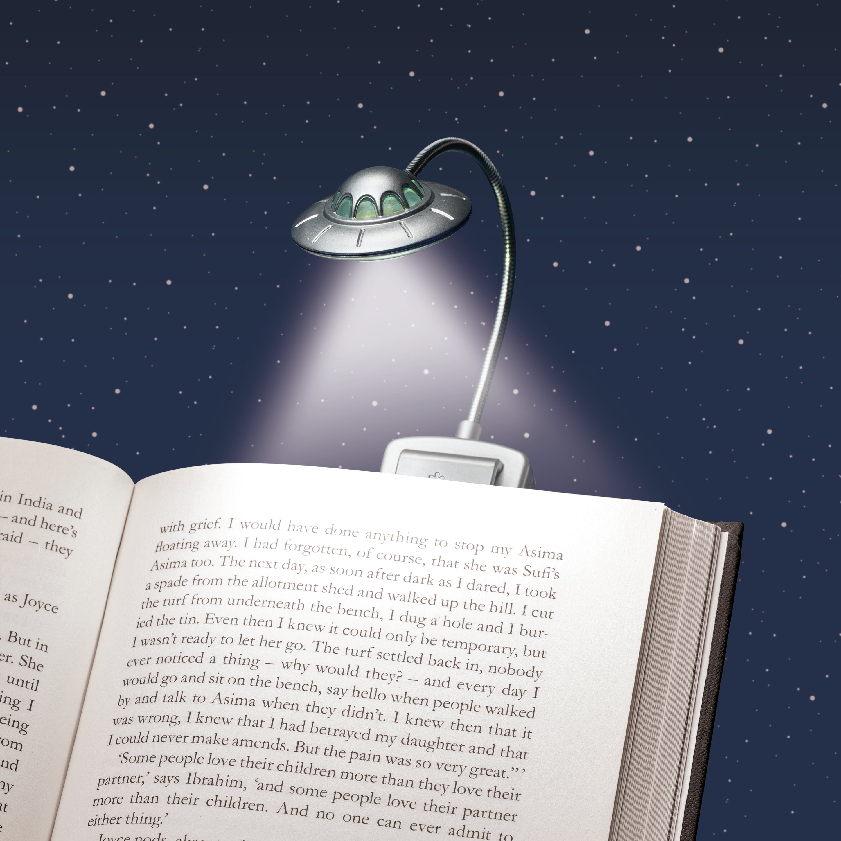 UFO-shaped reading lamp on an open book with a starry night background