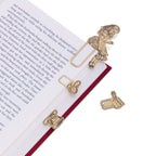 Brass metal bookmarks on an open book.