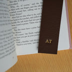 Brown leather bookmark with initials 'AT' on an open book | Bookmark & Co