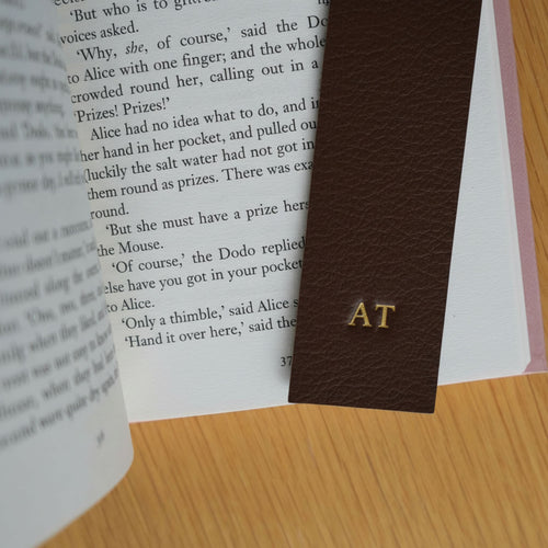 Brown leather bookmark with initials 'AT' on an open book | Bookmark & Co