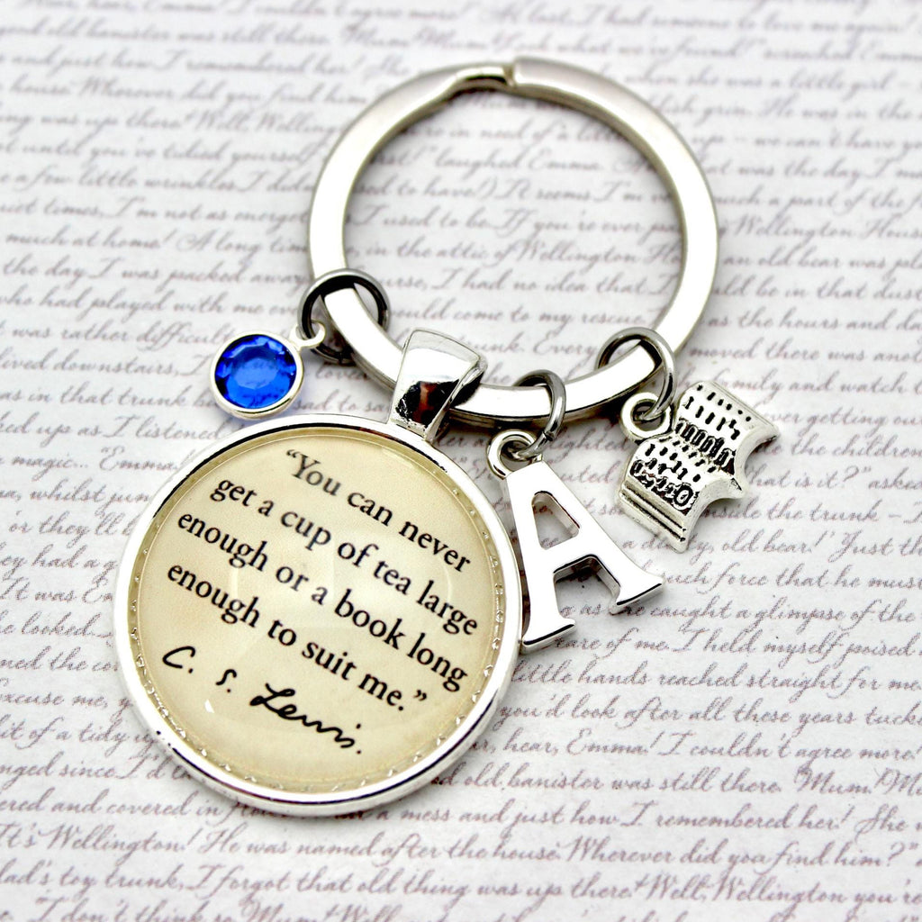Keychain with circular charm featuring a quote and letter 'A' charm on a textured background.