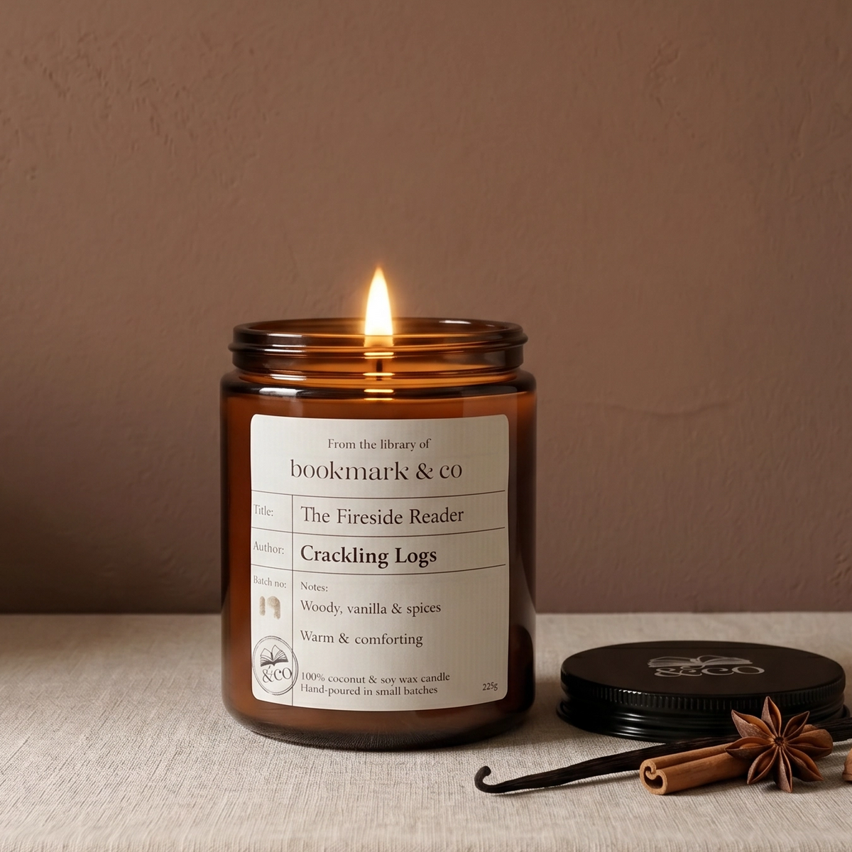 Candle in a glass jar with a label on a textured surface against a plain background