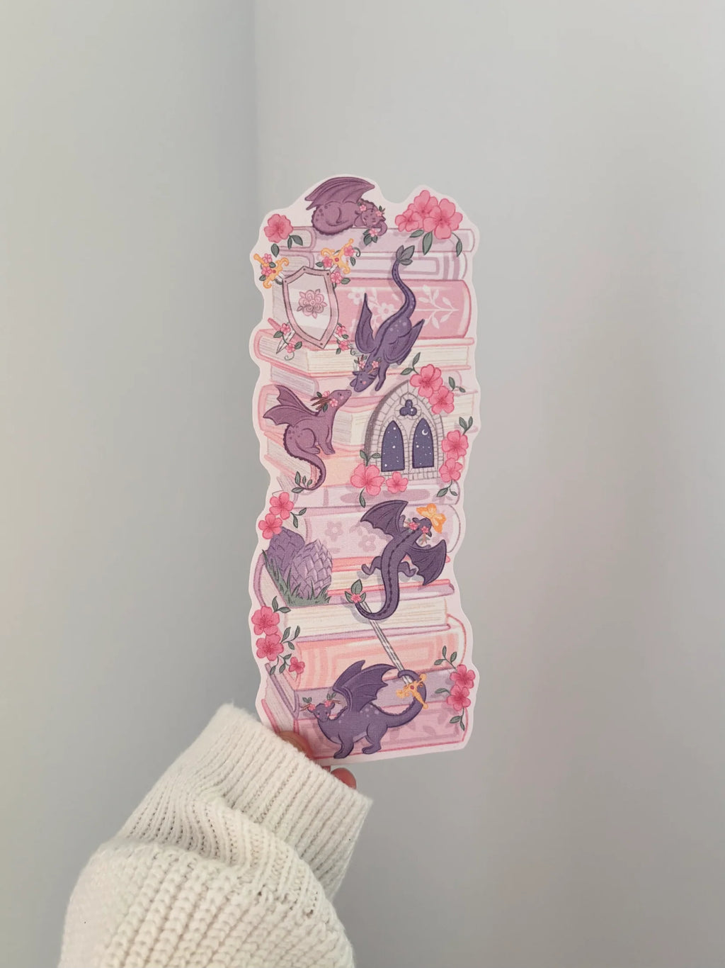 Decorative pink and purple dragon book stack bookmark being held