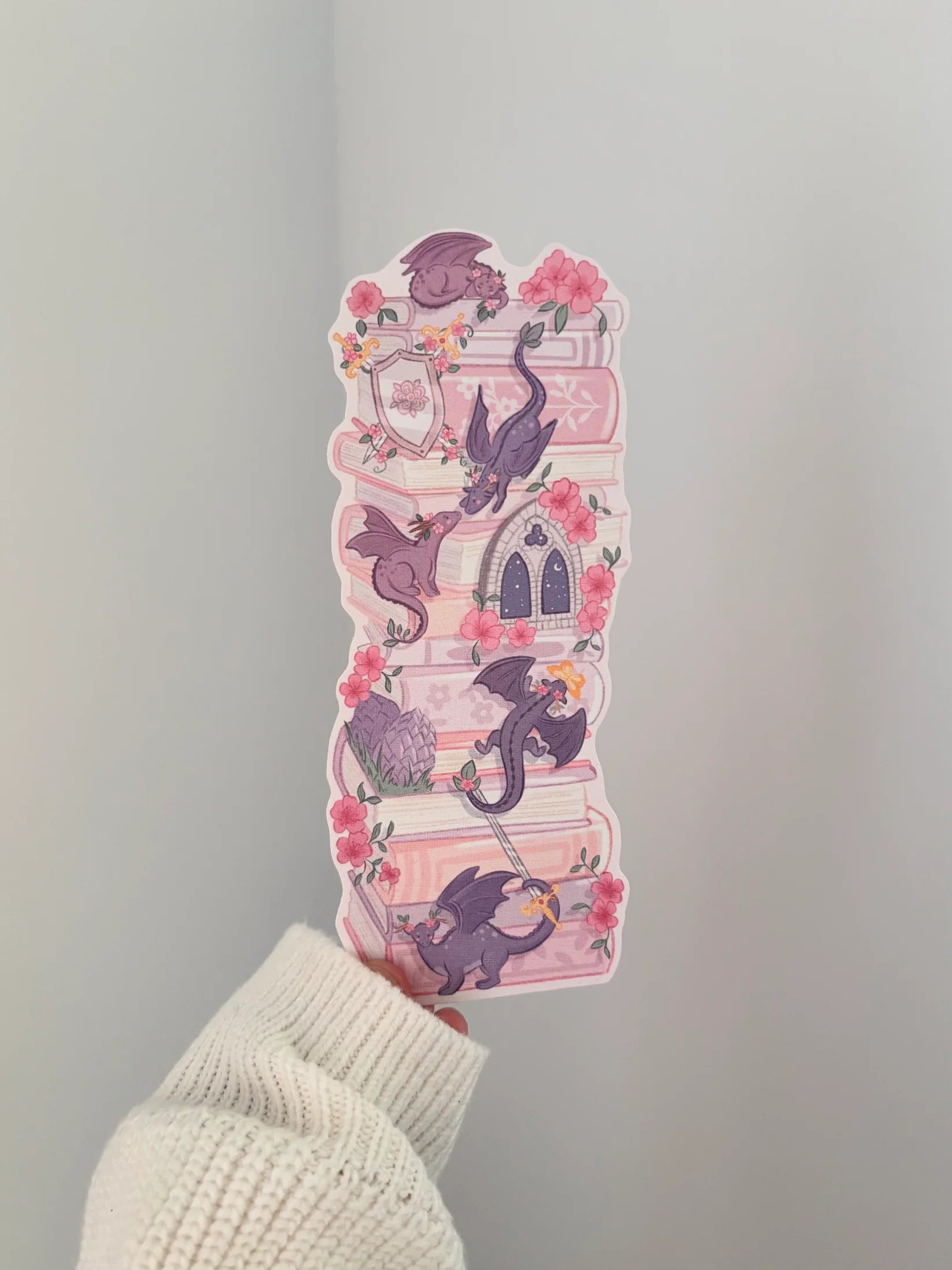 Decorative pink and purple dragon book stack bookmark being held