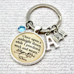 Keychain with circular pendant featuring text and small charms on a script background