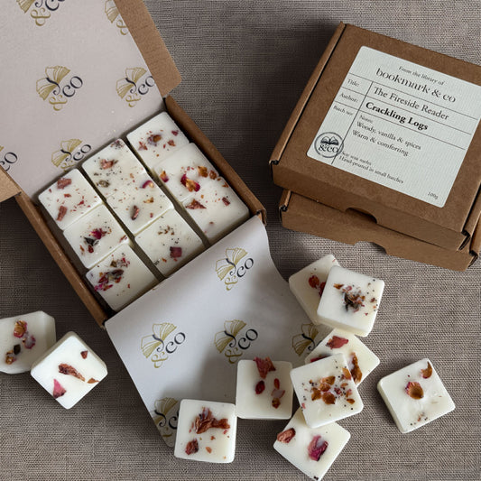 White wax melts with dried rose petals displayed in an open box and on a branded kraft box lid, arranged on a neutral fabric background.