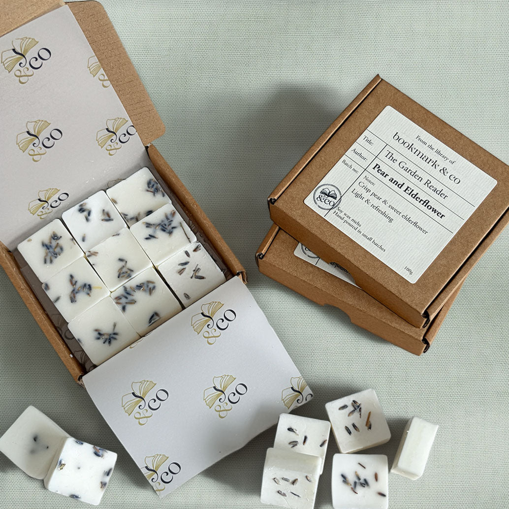 A styled flat-lay of soap bars from the brand 'bookmark & co' in 'Peony and Elderflower' scent. The white rectangular soaps are decorated with black and purple butterfly details.