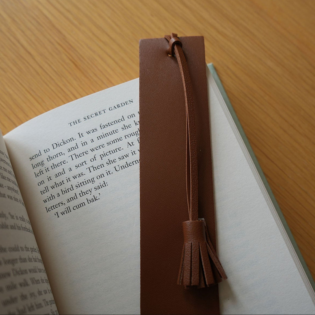 Open book with a brown leather bookmark on a wooden surface