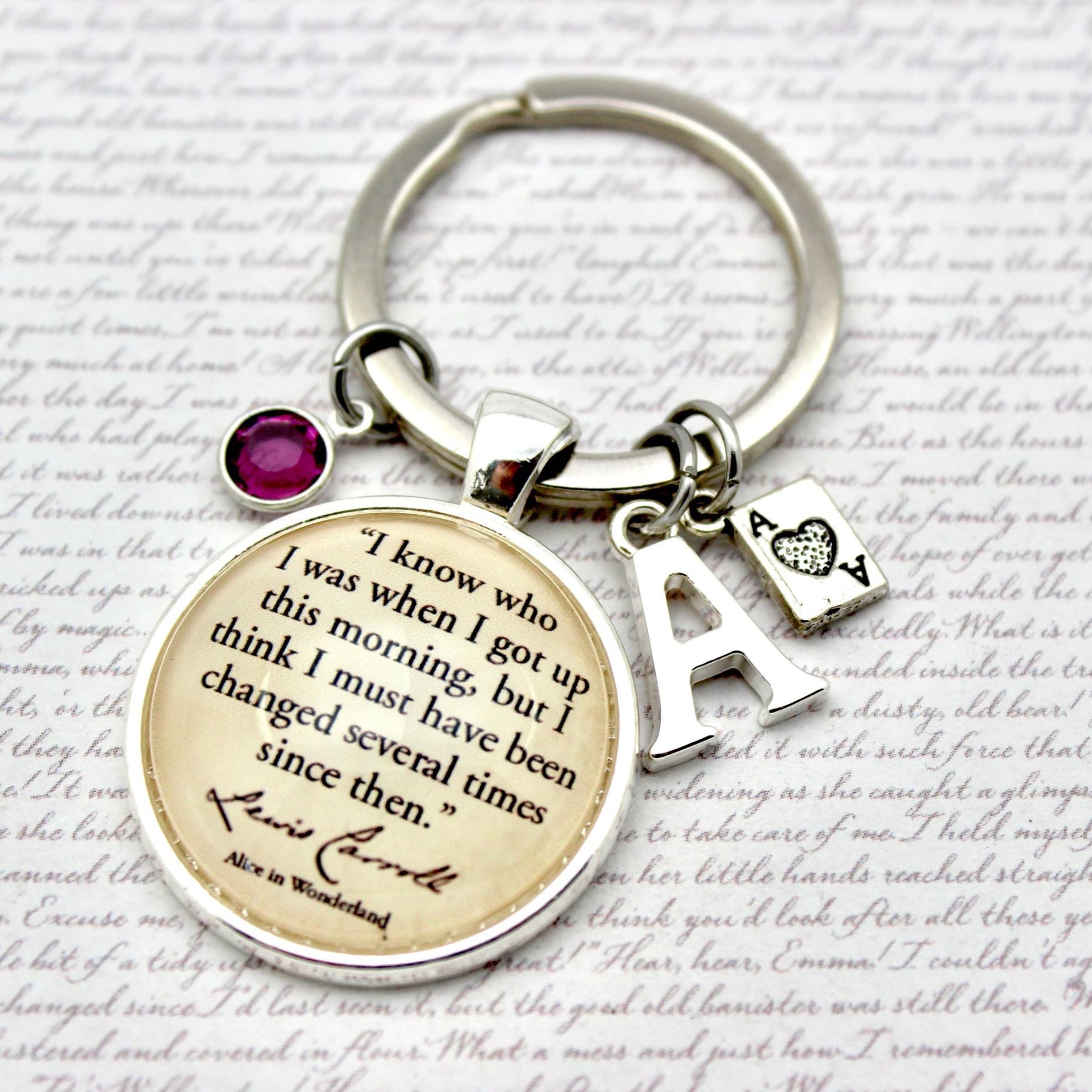 Keychain with circular charm featuring a quote and letter 'A' charm on a textured background.