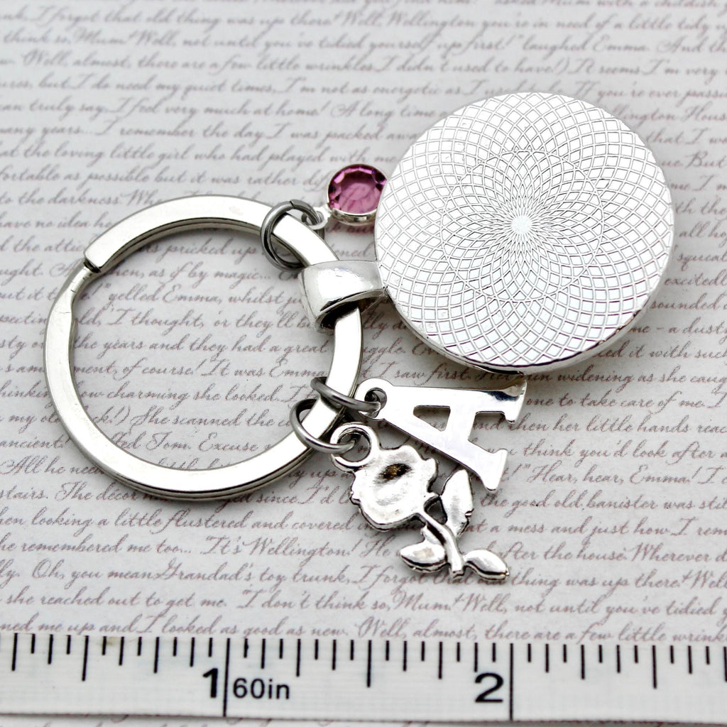 Keychain with letter 'A' and gemstone on a textured surface with text