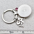 Keychain with letter 'A' and gemstone on a textured surface with text