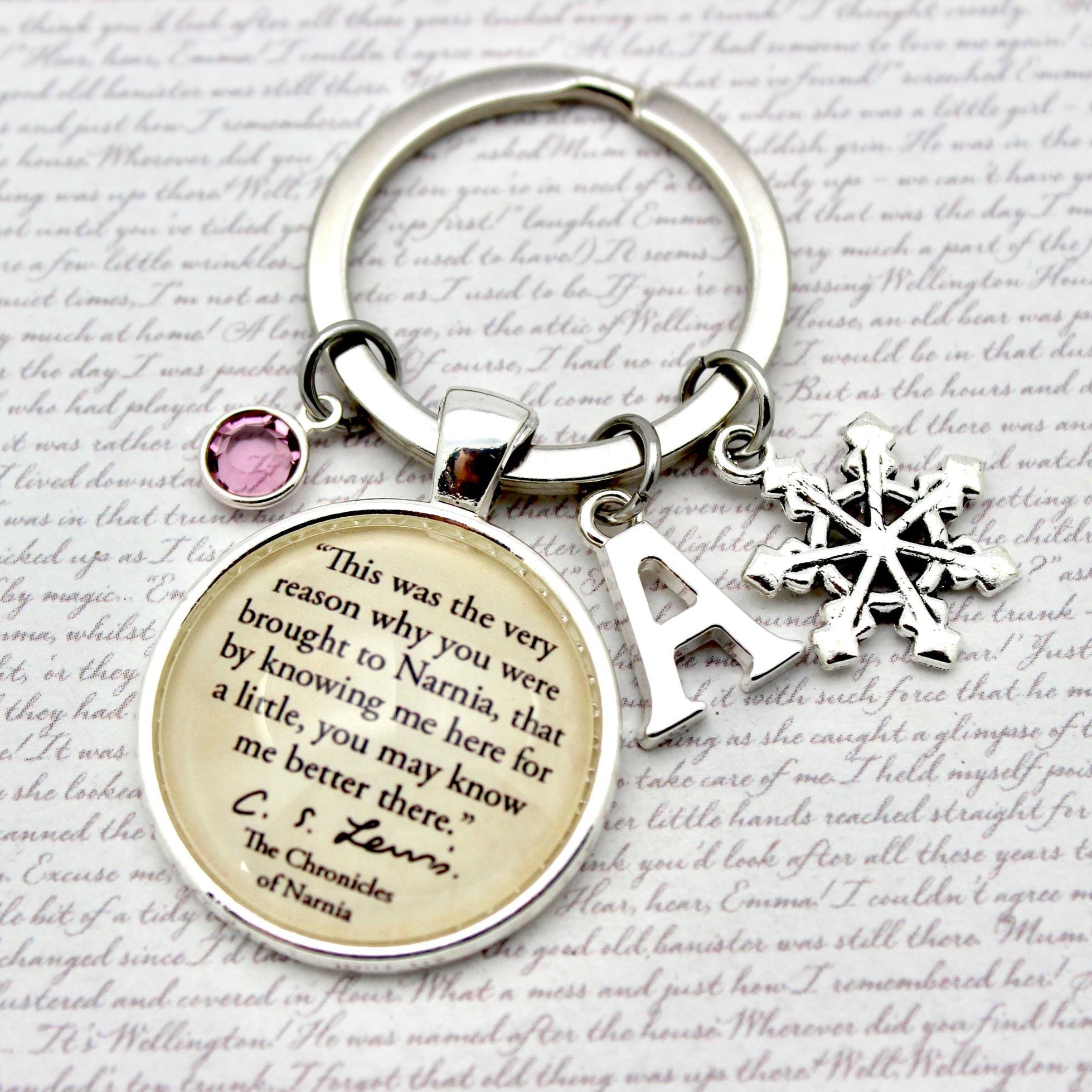 Keychain with circular charm featuring text, snowflake charm, and letter 'A' on a textured background.