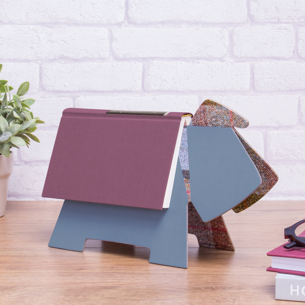 Color swatch book with different colored pages on a wooden surface against a white brick wall.