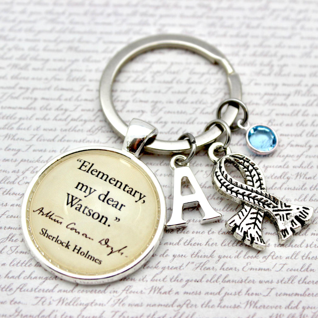 Keychain with 'Elementary, my dear Watson' quote and other charms on a script background