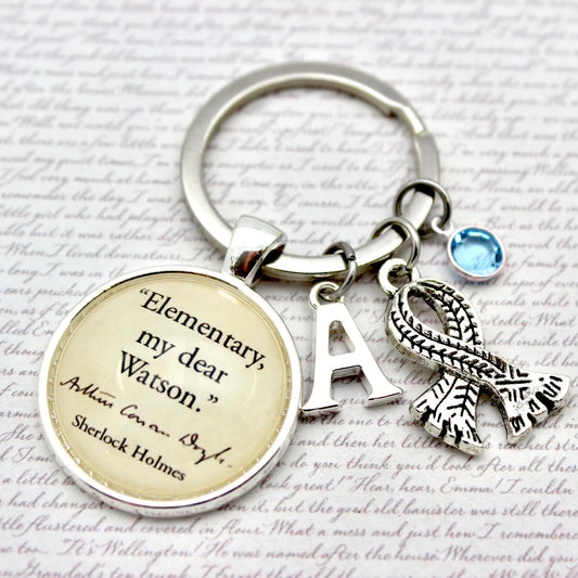 Keychain with 'Elementary, my dear Watson' quote and other charms on a script background