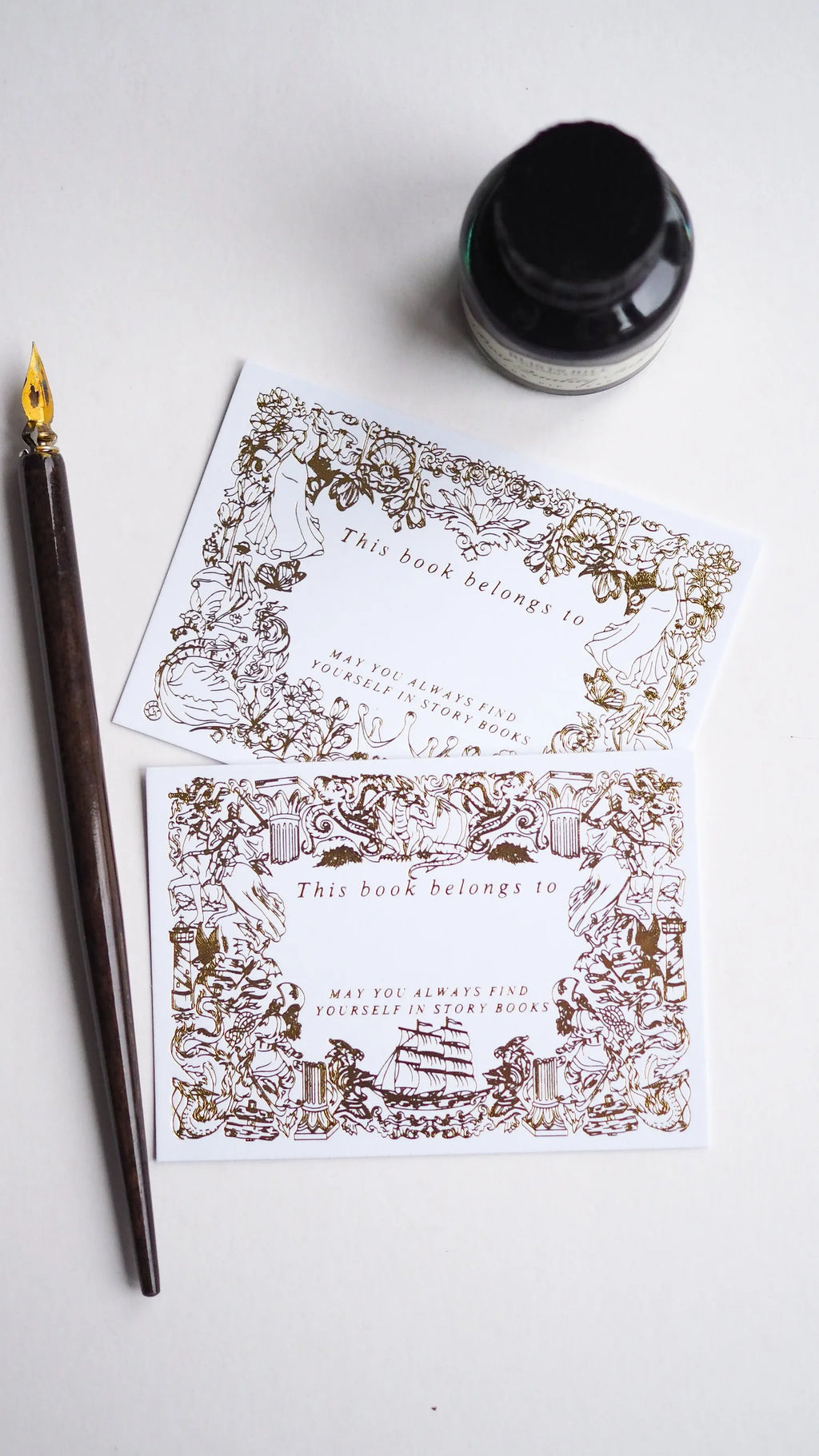 Decorative bookplates with intricate designs on a white surface with a fountain pen and ink bottle.