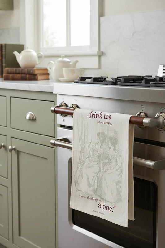 Tea towel with illustration of two women and text about drinking tea, on a white background