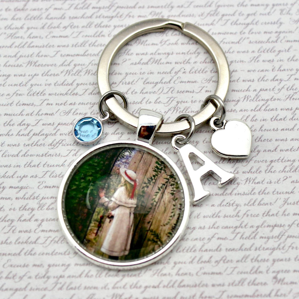 Keychain with circular charm featuring a painting of a woman, surrounded by decorative elements on a textured background.