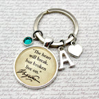 Keychain with motivational quote and letter 'A' charm on a textured background