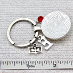 Keychain with round silver charm, red gem, and letter charms 