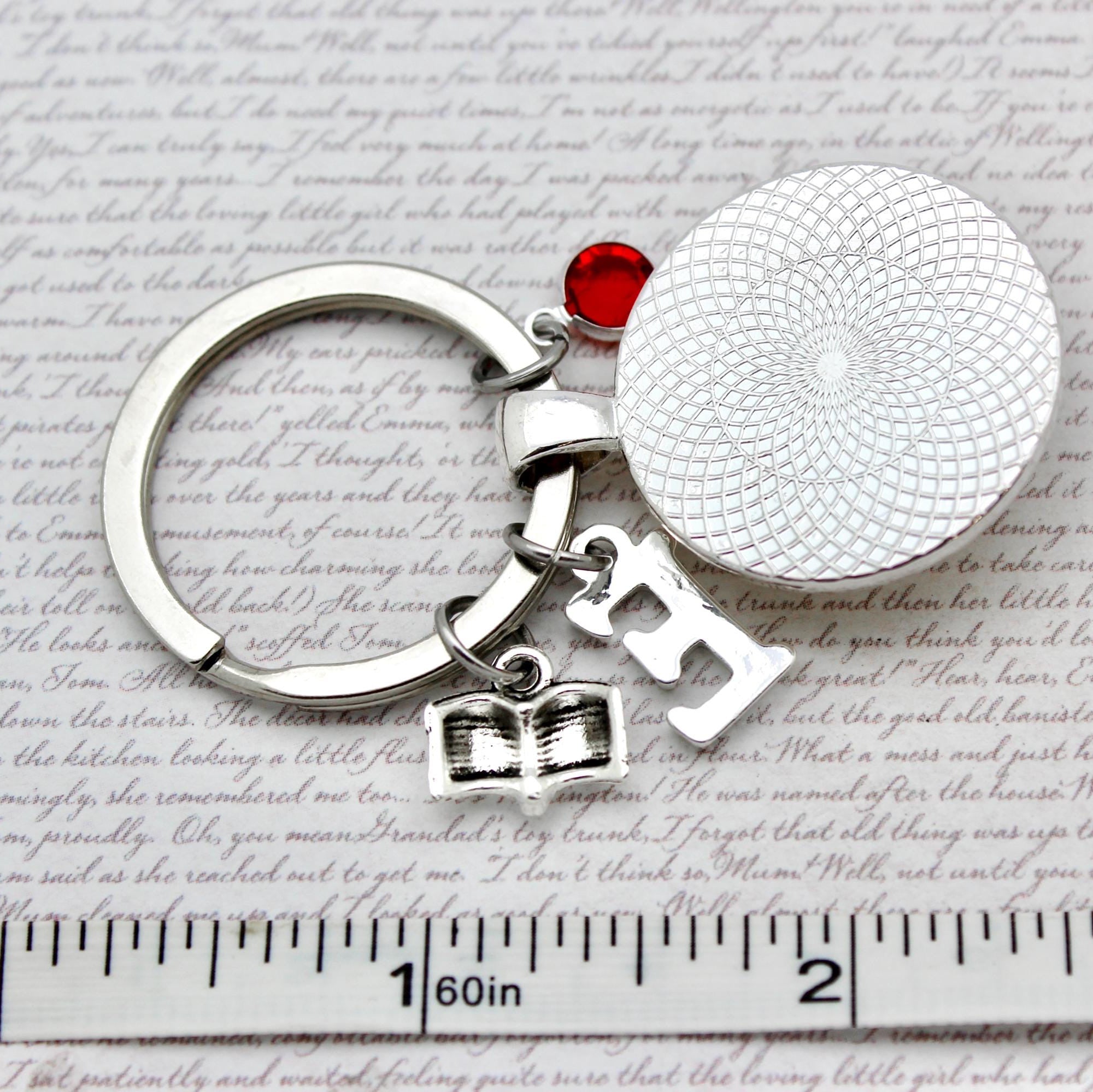 Keychain with round silver charm, red gem, and letter charms 