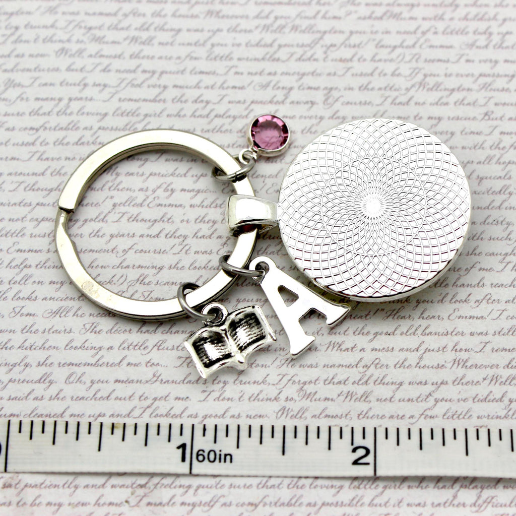 Silver keychain with round charm and letter 'A' on a textured surface
