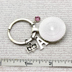 Silver keychain with round charm and letter 'A' on a textured surface