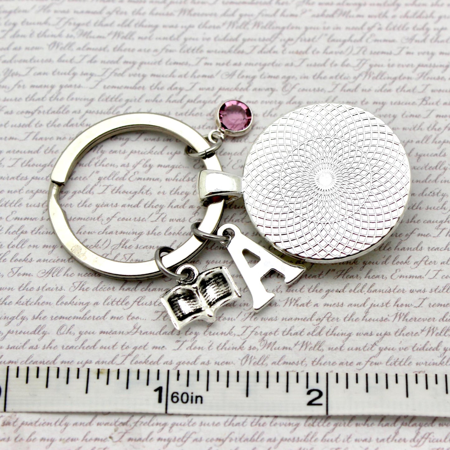 Silver keychain with round charm and letter 'A' on a textured surface