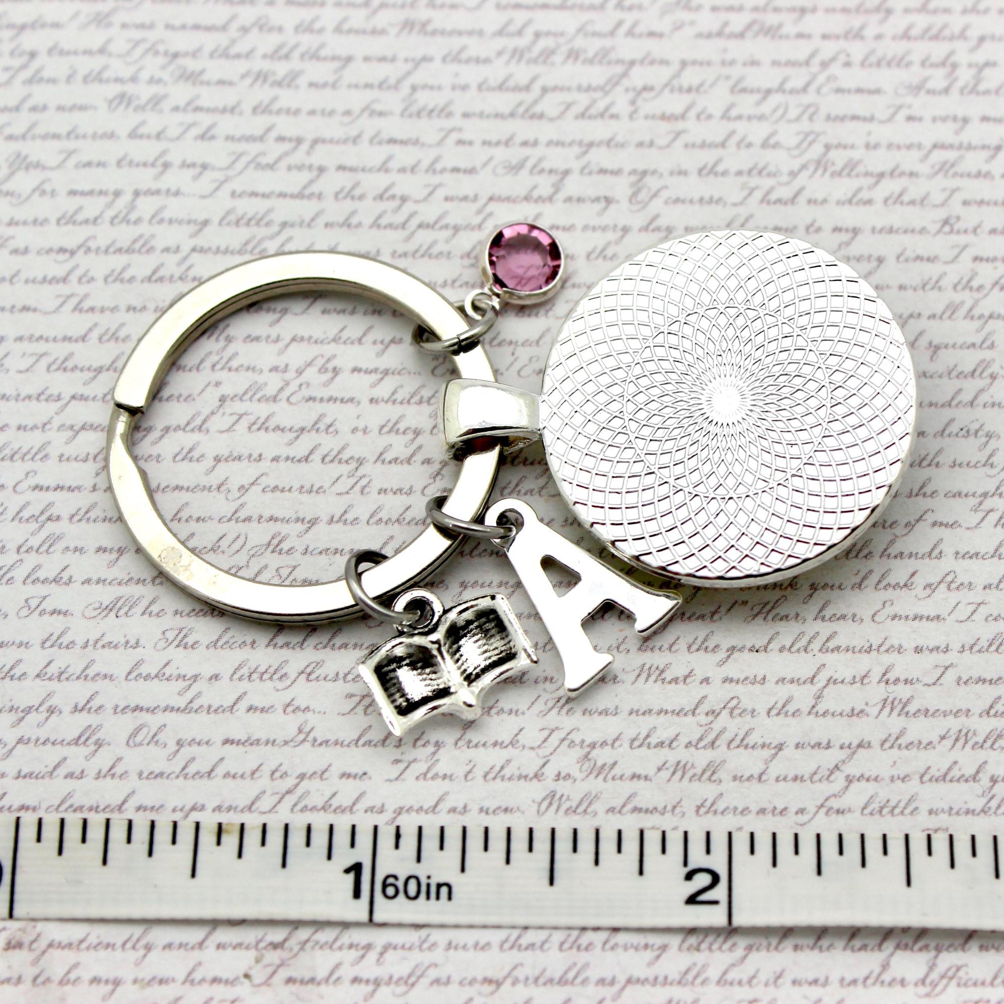Silver keychain with round charm and letter 'A' on a textured surface