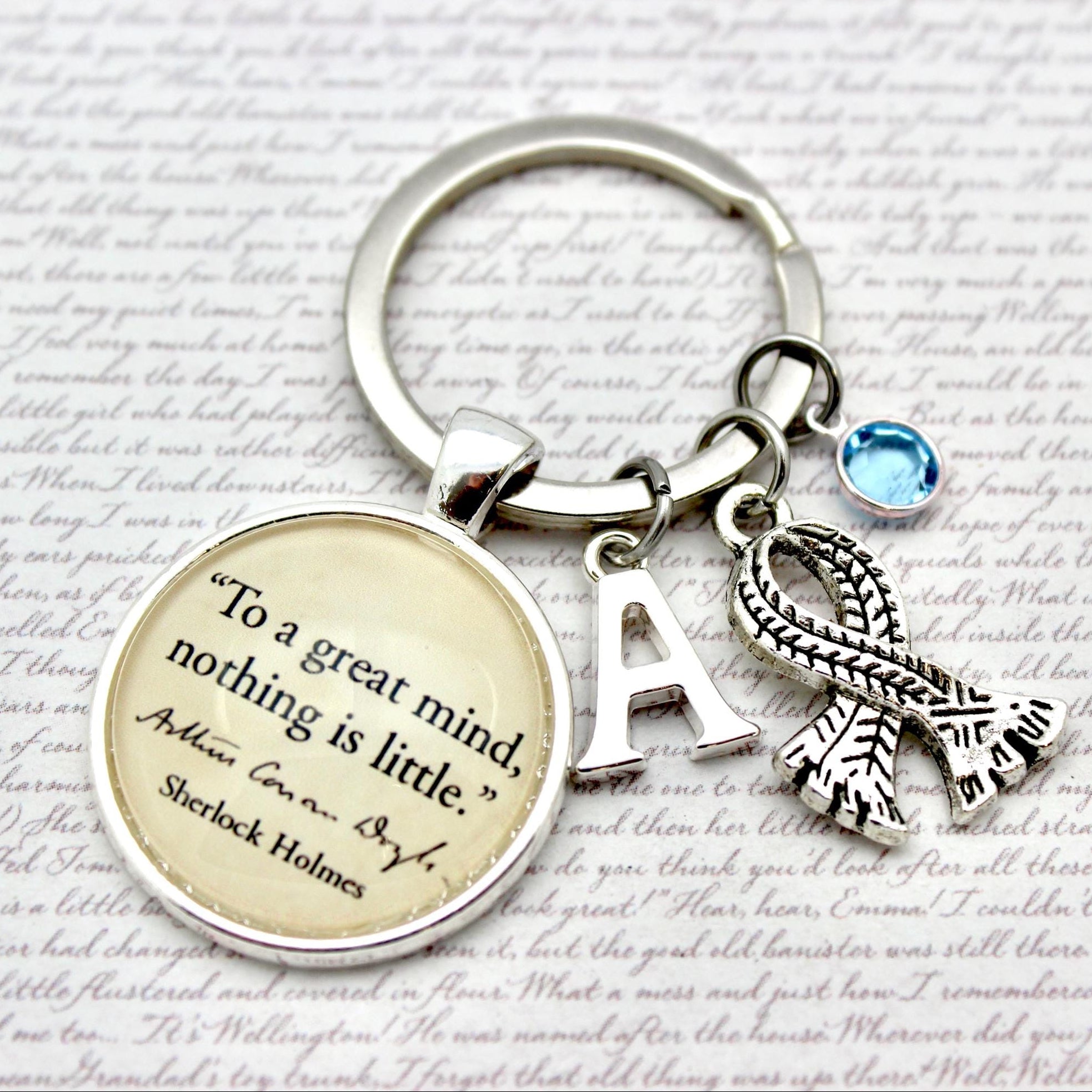 Keychain with inspirational quote, initials, and scarf charm on a script background