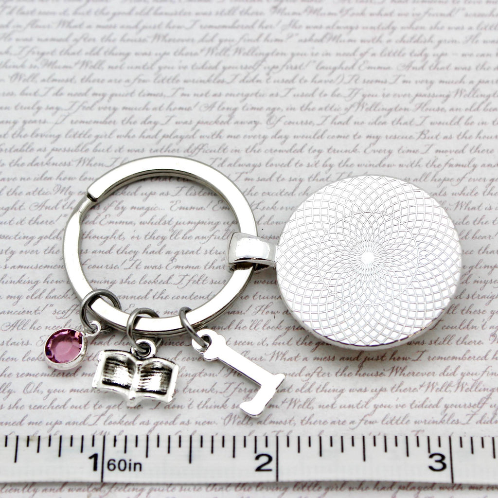 Silver keychain with round pendant and heart charm on a textured surface with text