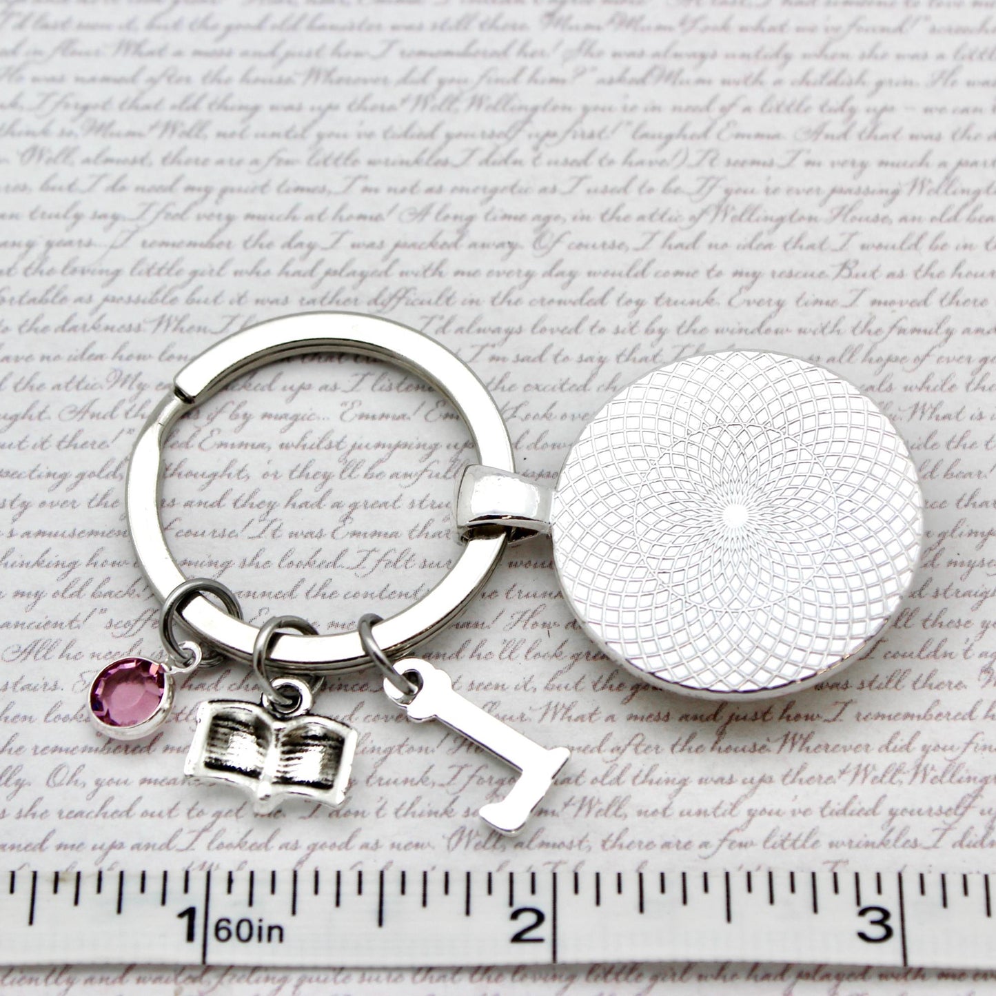 Silver keychain with round pendant and heart charm on a textured surface with text