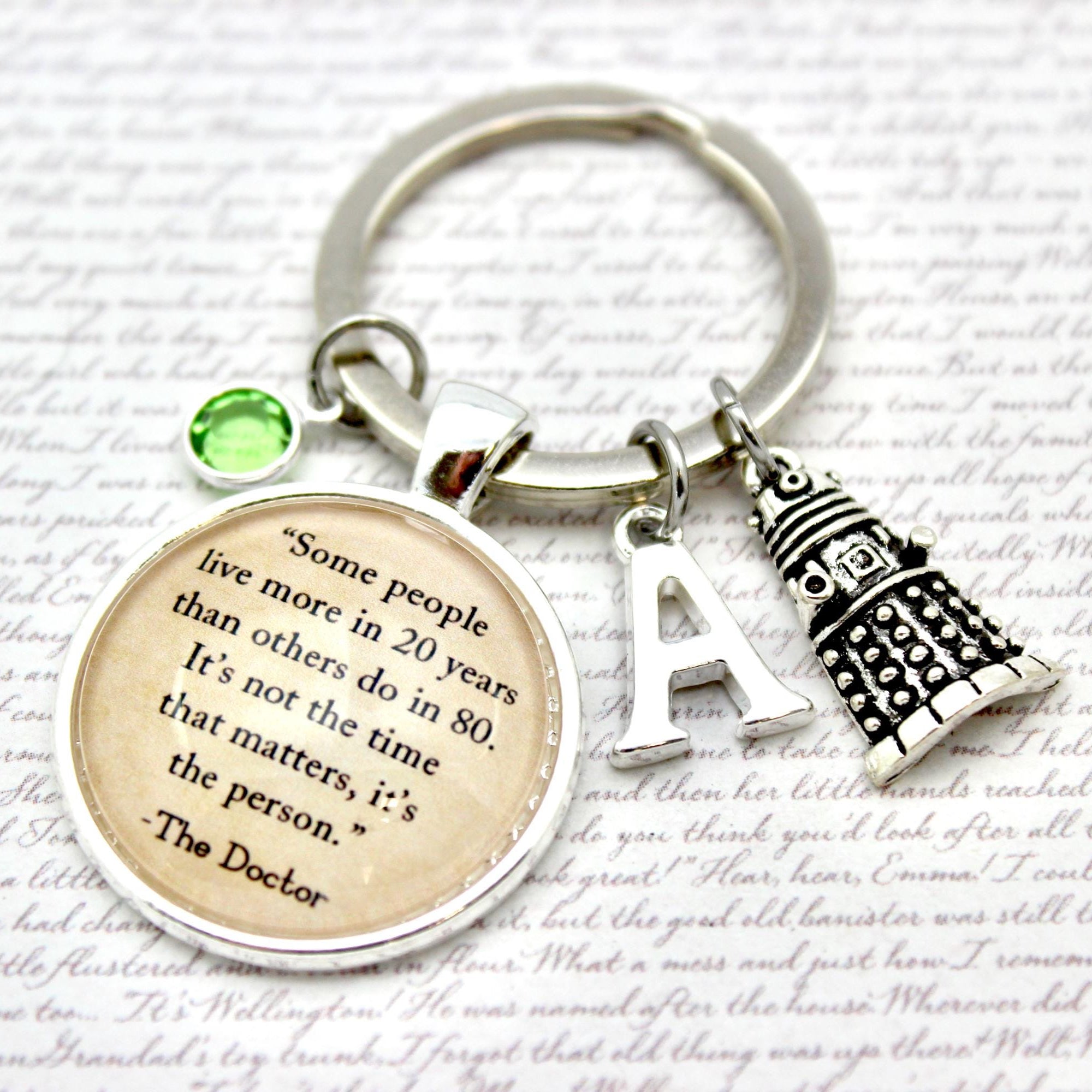 Keychain with inspirational quote, clock charm, and letter 'A' charm on a textured background.